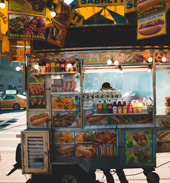 A hot dog stand with a person behind it.