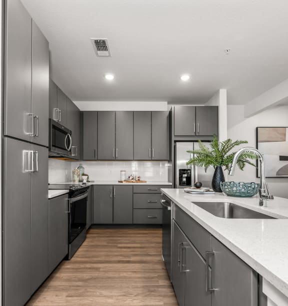 a kitchen with gray cabinets and white countertops and a sink