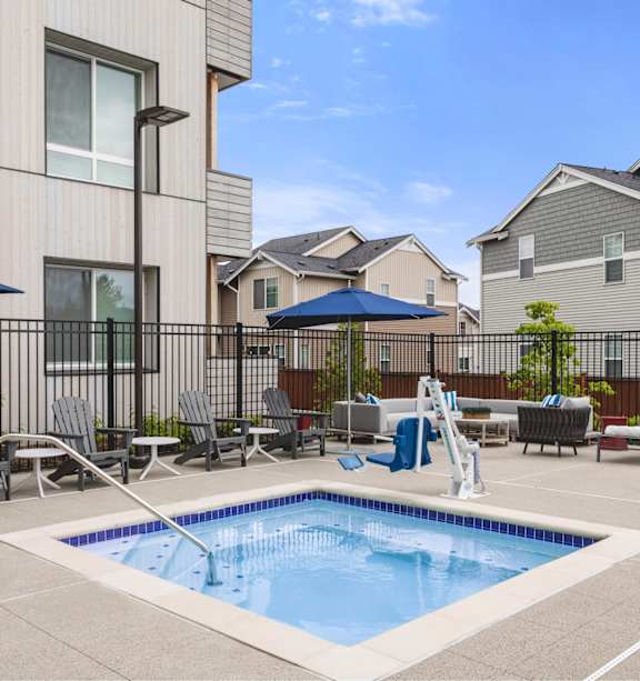 A swimming pool in a residential area surrounded by chairs and umbrellas.