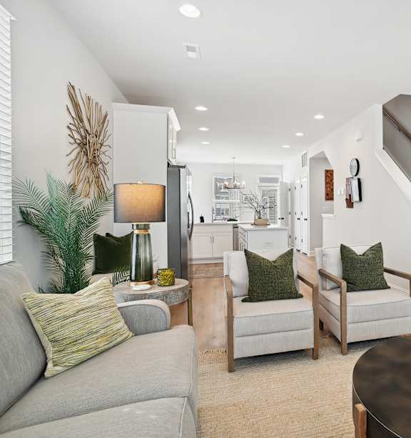A living room with a grey couch, a coffee table, and a staircase.