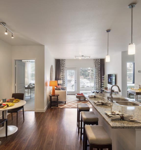 an open kitchen and living room with a large granite counter top