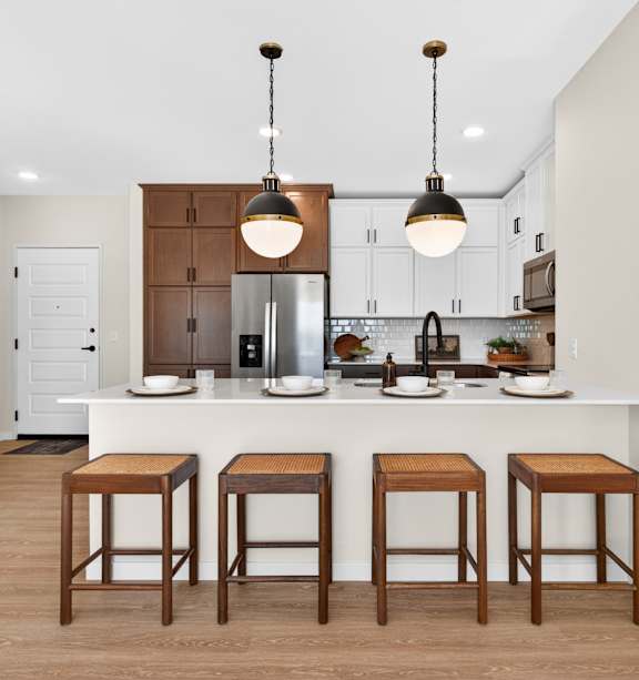 A kitchen with a white island and brown stools.