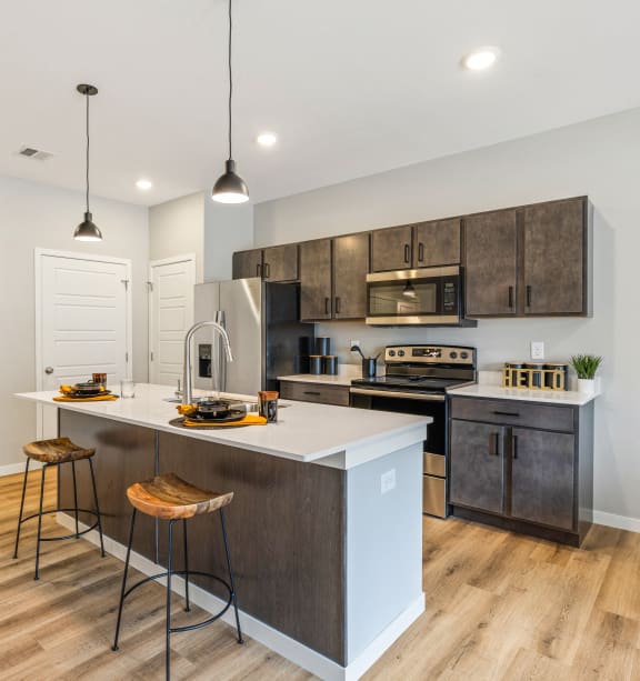 an open kitchen with a large island with three stools at EagleRidge Plaza Residences, Fargo, 58104