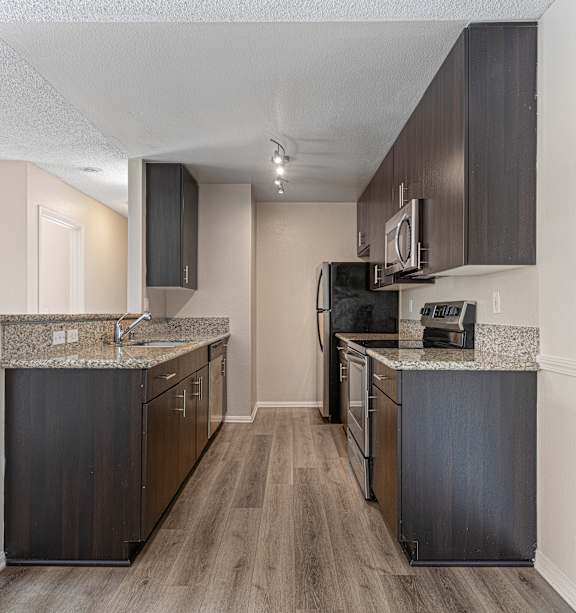 A kitchen with dark wood cabinets and a granite countertop.