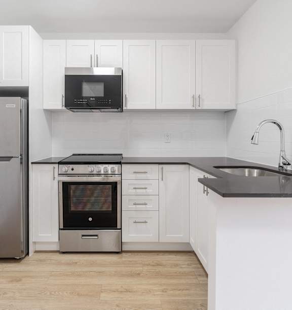 the living room and kitchen of an apartment with wood floors and white cabinets at 608 Church Apartments, Toronto, ON, M4Y 2E7