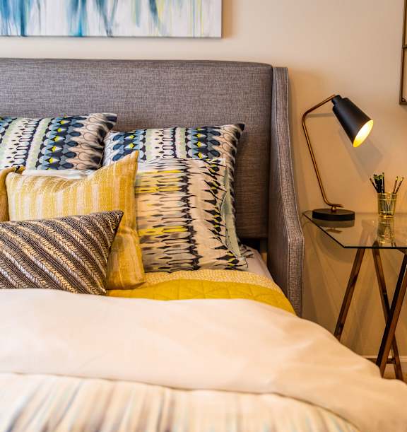 A bed with a grey headboard and a yellow pillow.