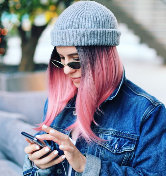 a woman with pink hair looking at her cell phone