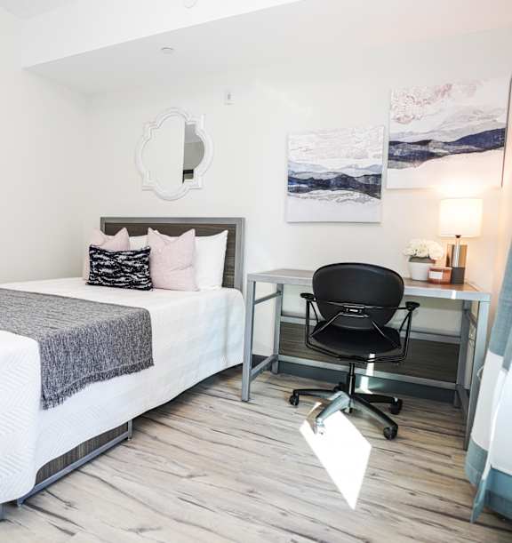 A bedroom with a bed, chair, and desk.