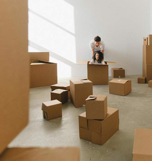 A man is standing on a box in a room full of boxes.