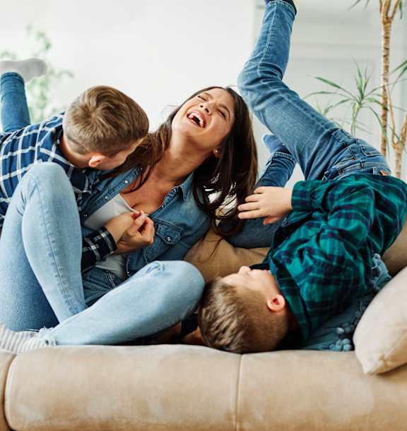 A family of three is lying on a beige couch.