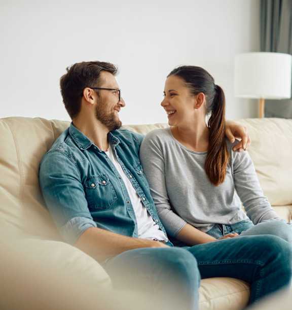 A man and a woman are sitting on a beige couch.