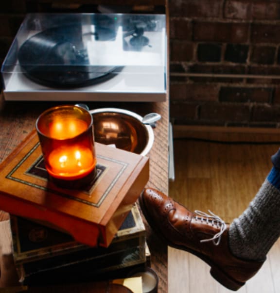 a candle lit on a table next to a pair of shoes