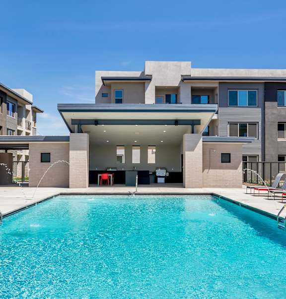 A swimming pool in front of a building with a red chair.