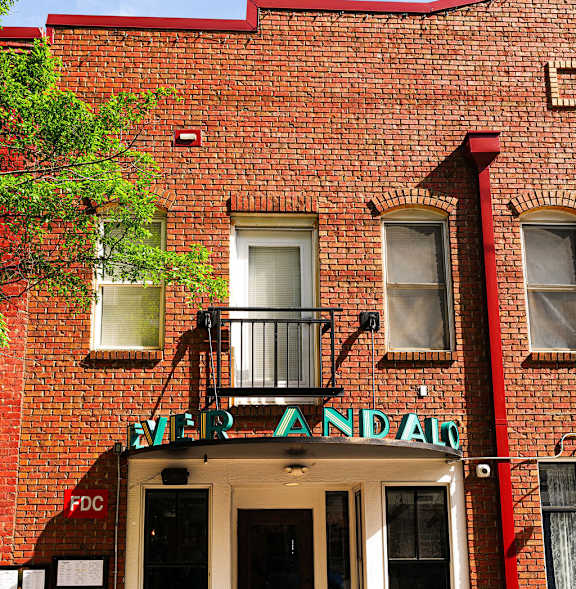 A red brick building with a balcony and a sign that says "The Andaz".