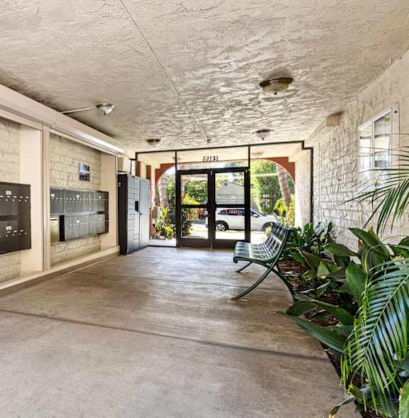 A concrete hallway with a bench and a door with a sign that says "ENTRANCE".