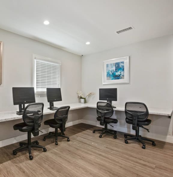an office with five chairs and computers in front of a window