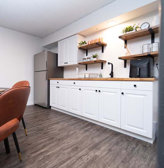 A kitchen with a brown chair and white cabinets.