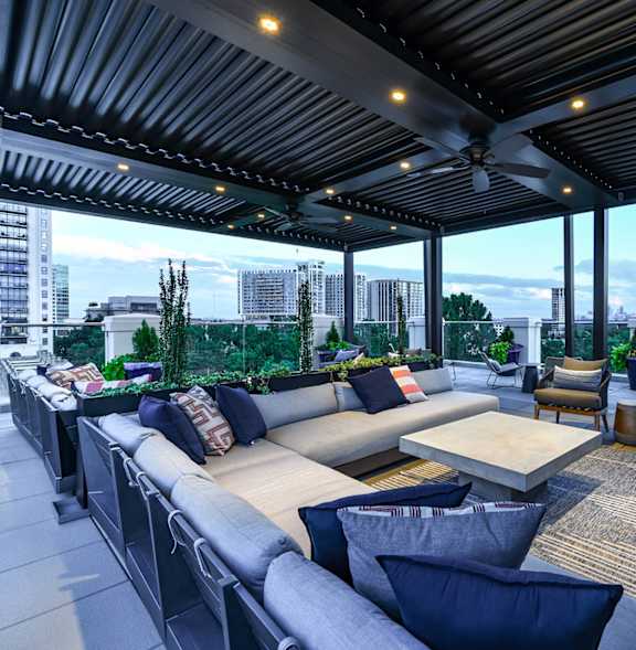 A patio with a couch and chairs with a view of the city.