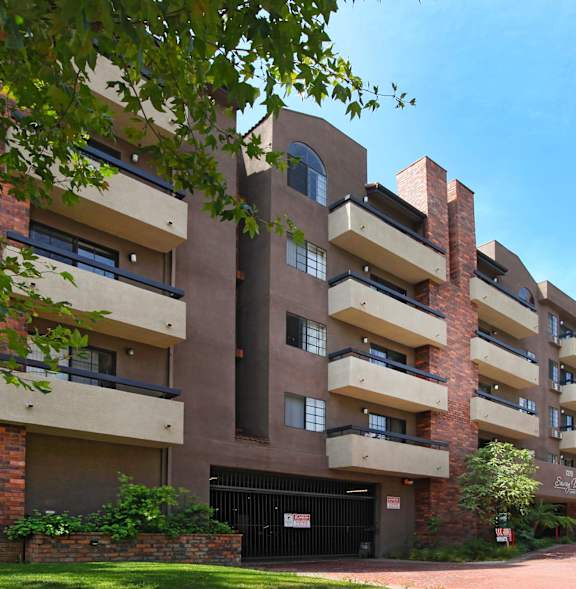 A large brick building with balconies and a black gate in front.