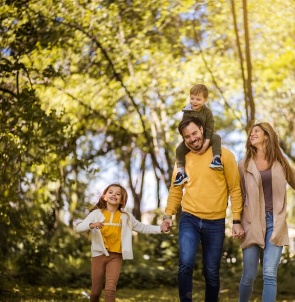 a family walking through the park with a child on their shoulders