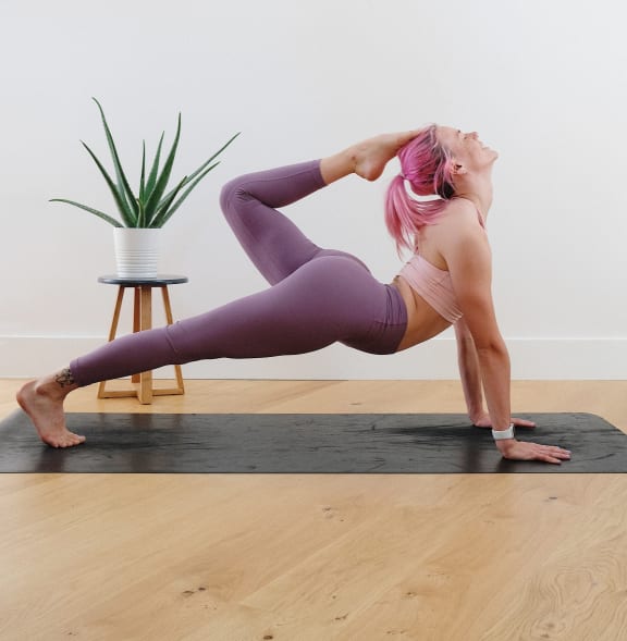 a woman in a yoga pose with a pineapple hanging above her head