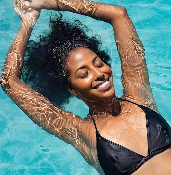 A woman in a black bikini is floating in a pool.