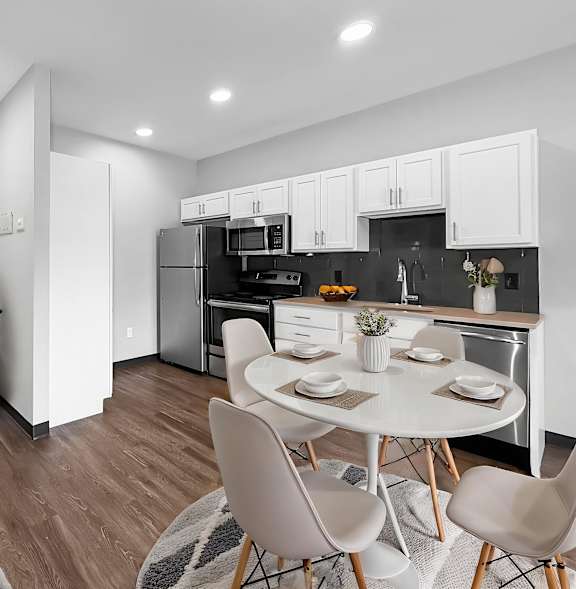 A modern kitchen with a dining table set for two.