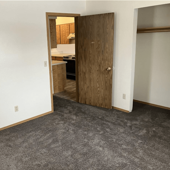 a bedroom with a door to a kitchen and a carpeted floor