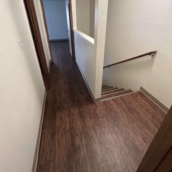 a hallway with wood flooring and white walls.