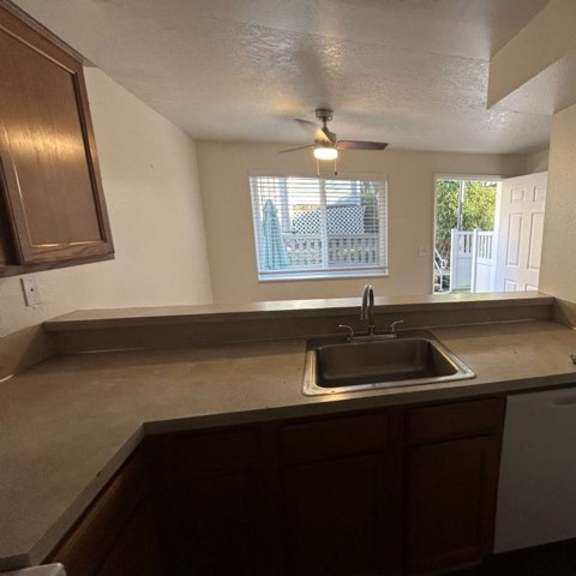 a kitchen with a brown countertop and a white dishwasher.