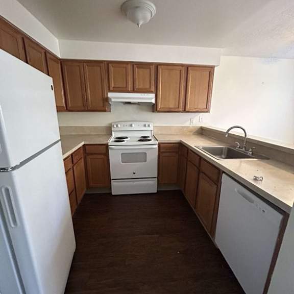 a white refrigerator stands in a kitchen with wooden cabinets.
