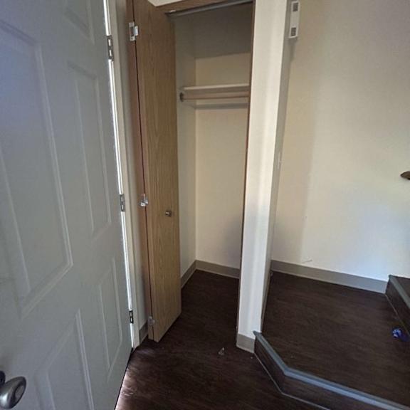 a white door is open to a hallway with a brown floor.