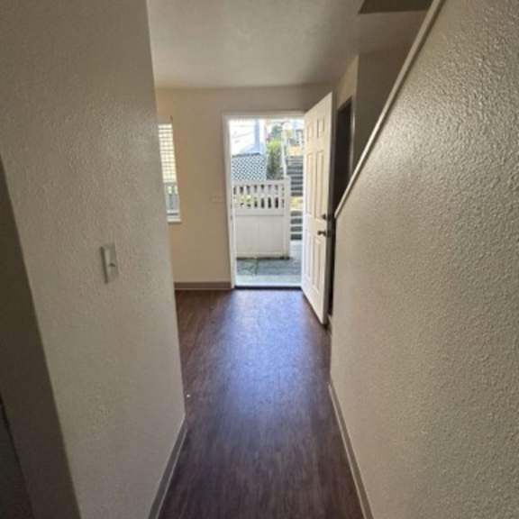 a hallway with a wooden floor and white walls.