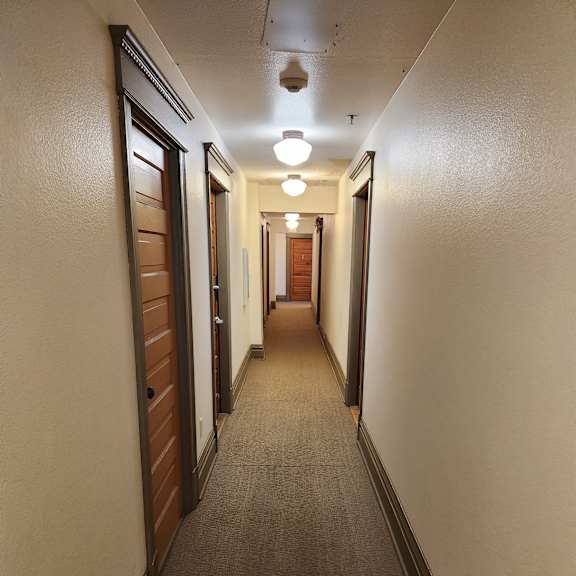 a long hallway with a brown floor and white walls.