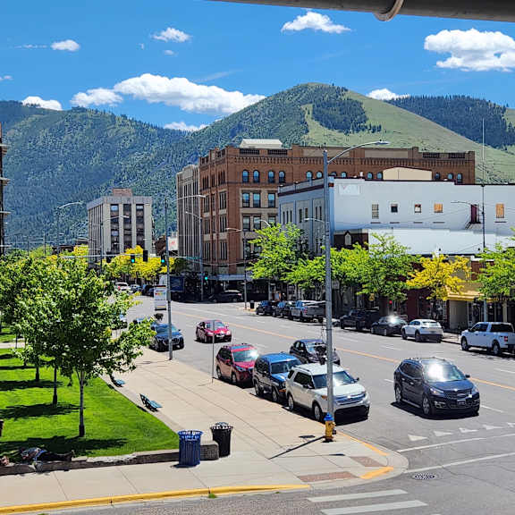 cars are driving on a street with buildings on either side.