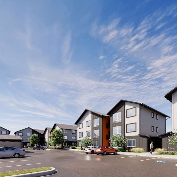 a modern apartment complex with a parking lot in front.
