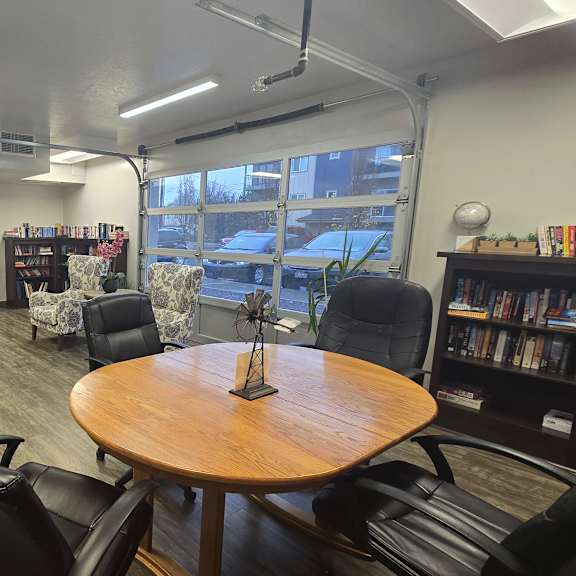 a room with a table, chairs, and bookshelves.