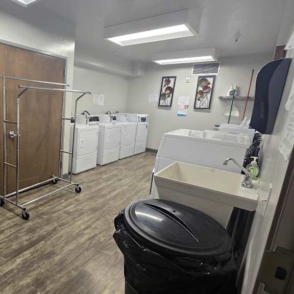 a laundry room with a washer and dryer, a black trash can, and a black chair.