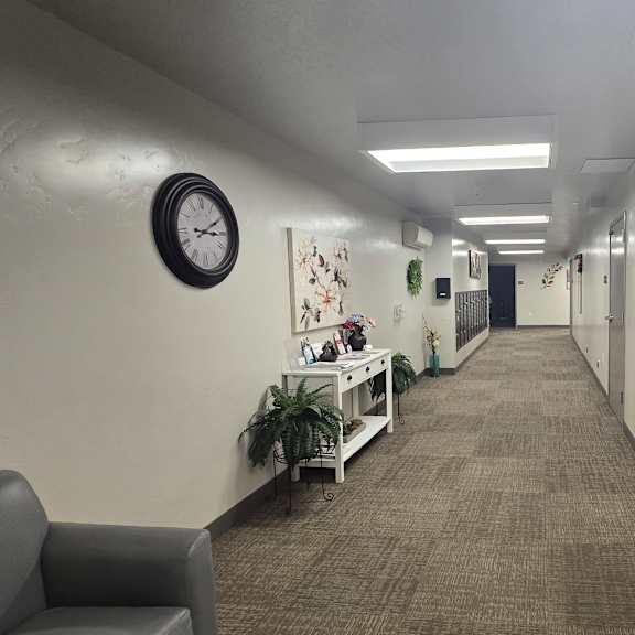 a long hallway with a clock on the wall and a wreath on the other wall.