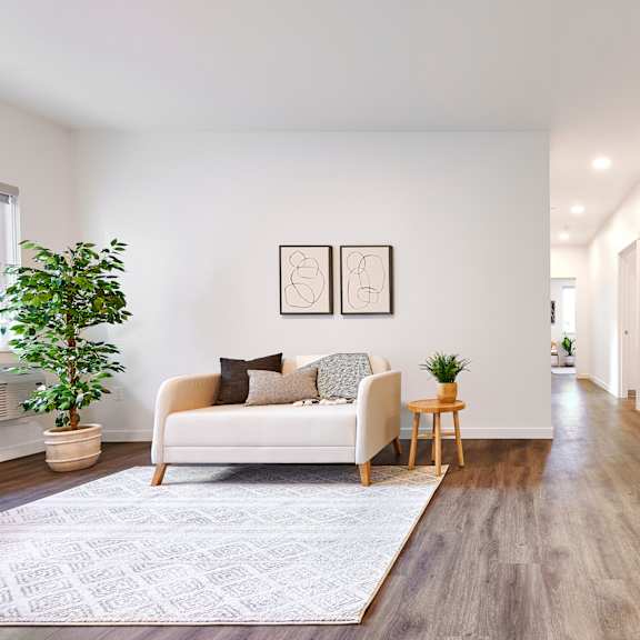 a living room with a couch and a rug and a kitchen with a refrigerator