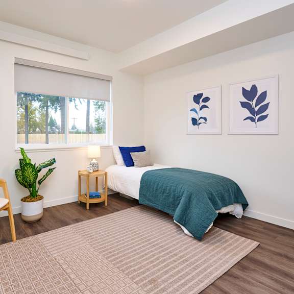 a bedroom with a bed and a chair and a window