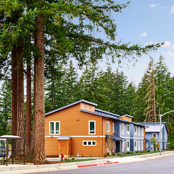 a row of houses on the side of a street with trees