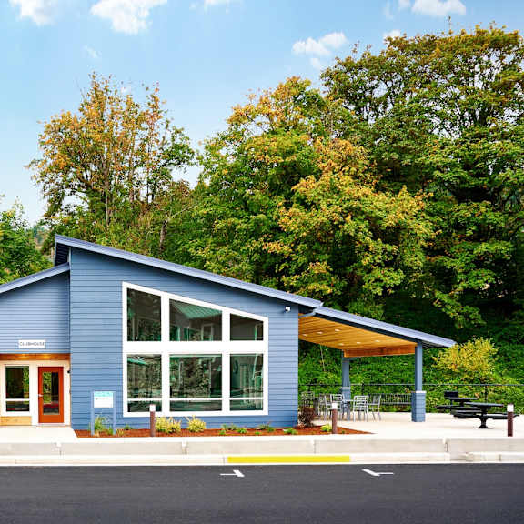 the exterior of a blue house with a large window and a porch