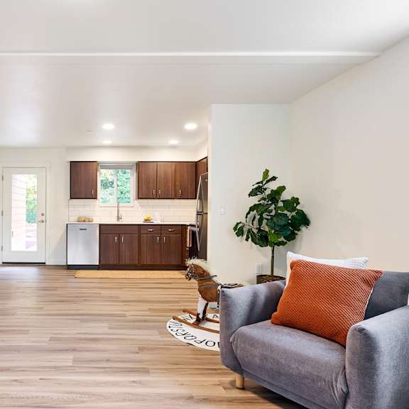 a living room with a couch and a chair in front of a kitchen