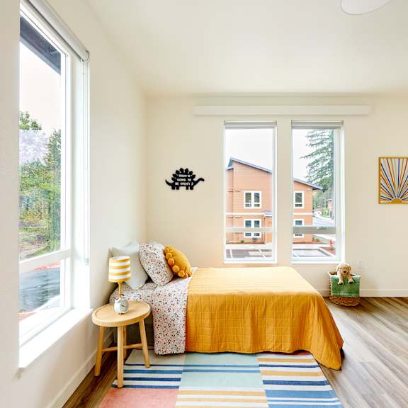 a bedroom with a yellow bed and two large windows