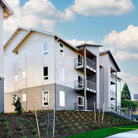 a row of three story apartments with balconies and a sidewalk