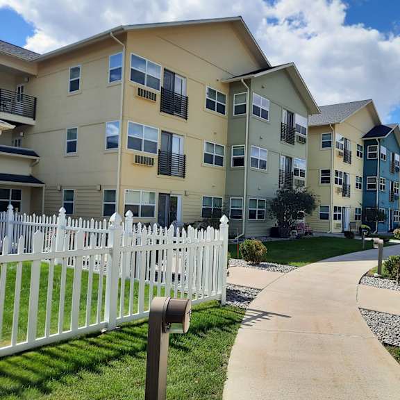 an exterior view of an apartment complex with a white picket fence
