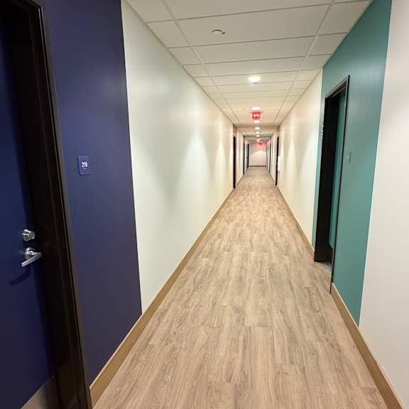a long hallway with wood floors and doors on both sides.