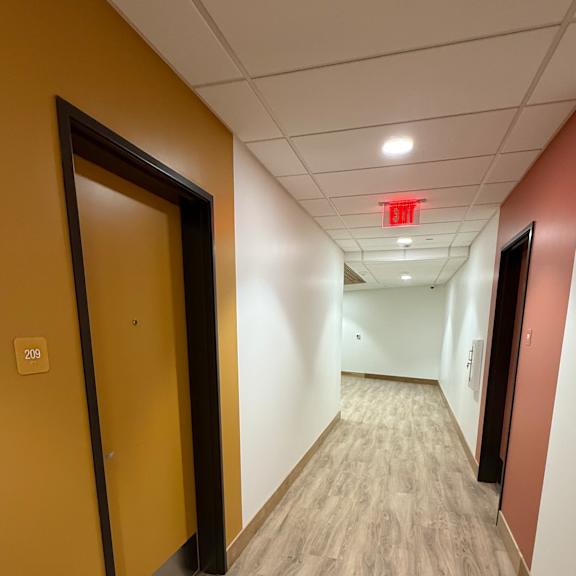 a long hallway with a red exit sign on the ceiling.