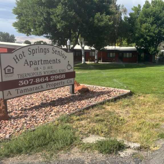 a sign for hot springs senior apartments is in front of a grassy area.